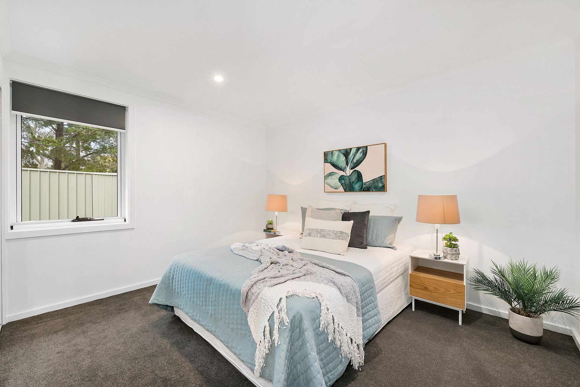 Bedroom with a bed, nightstands, and window, neutral color scheme, with a plant in a pot.