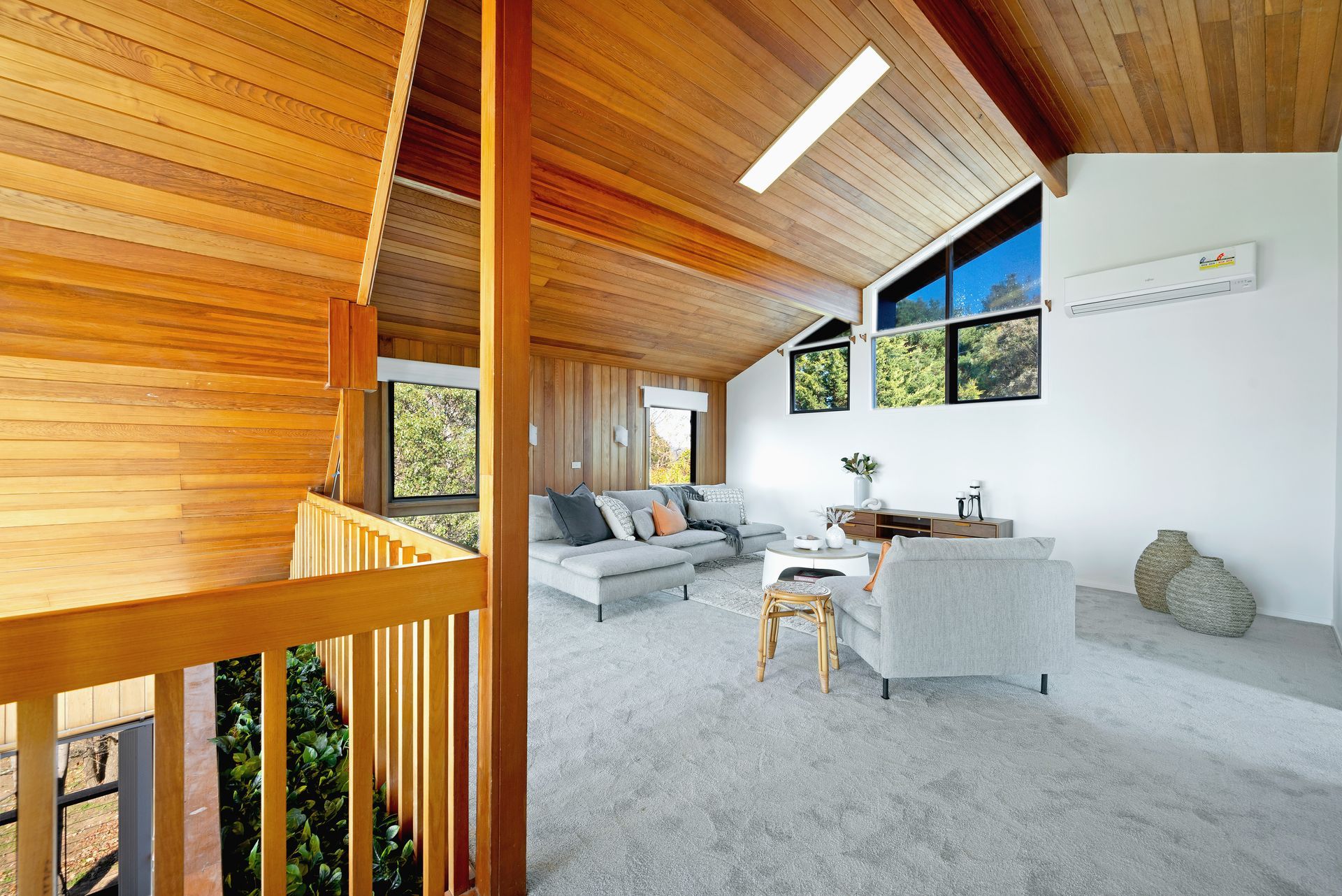 Interior with wood paneling, open to a living area with a couch, armchair, windows, and light gray carpet.