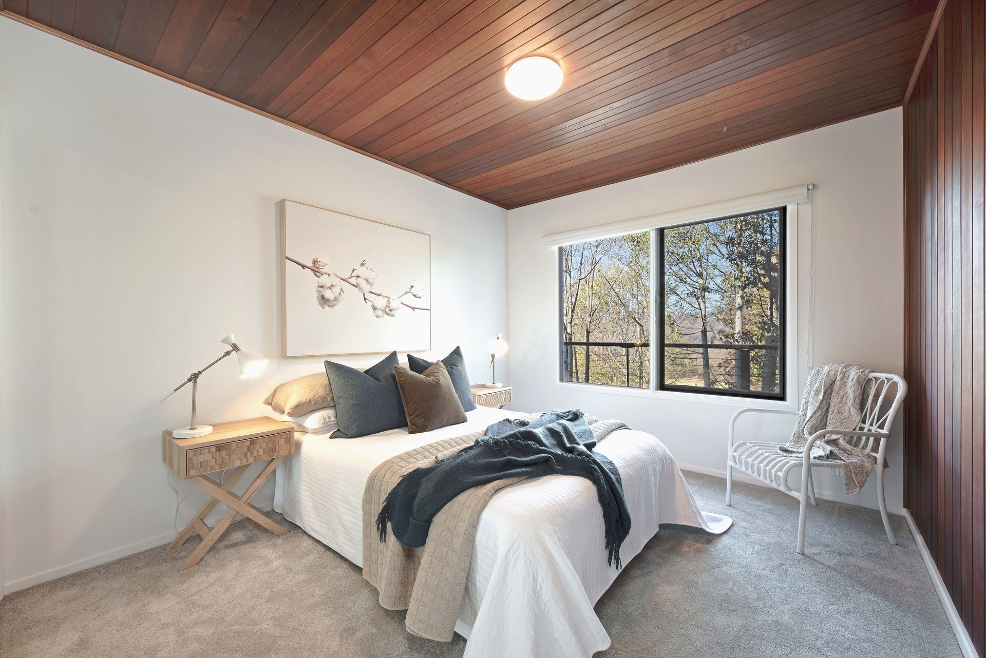 Bedroom with white walls, wood ceiling, bed, window, and armchair.