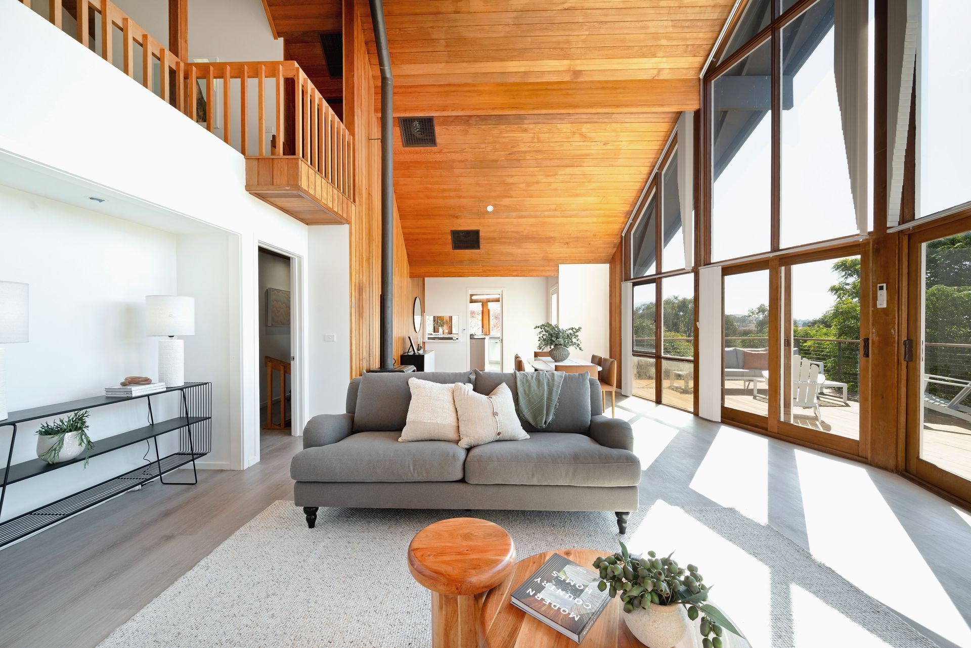 Living room with pink wall, large windows overlooking a yard, and neutral-toned furniture.