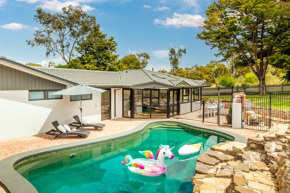 Swimming pool with inflatable unicorn and house in background.