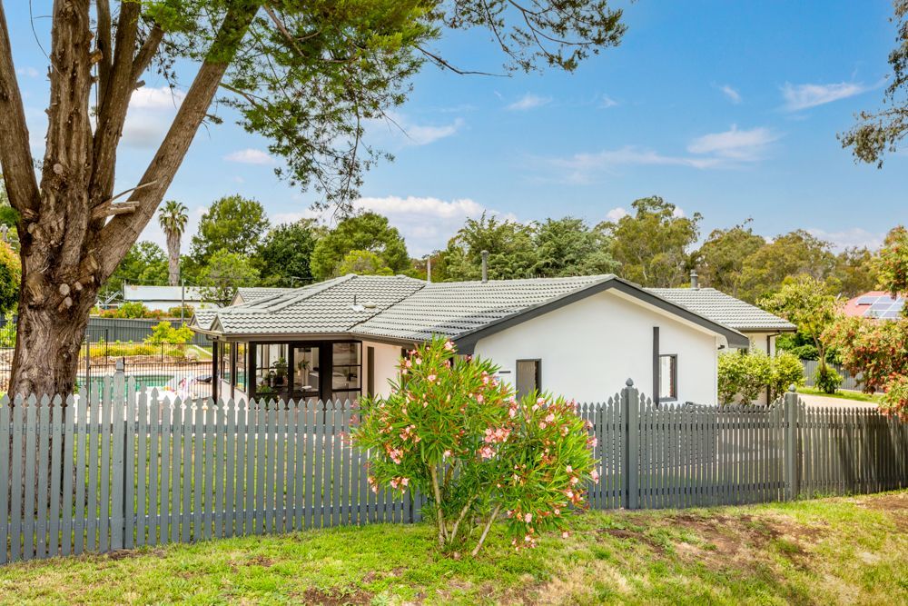 White house with gray roof behind a gray picket fence, sunny day.