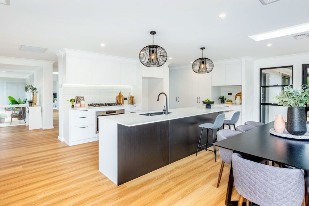 White kitchen with breakfast bar, stools, and open door to an outdoor patio with furniture.
