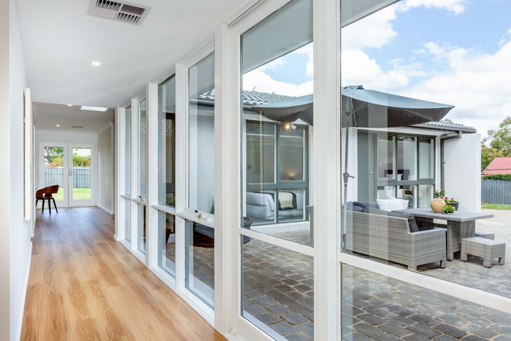 Hallway with large windows overlooking outdoor patio with furniture.
