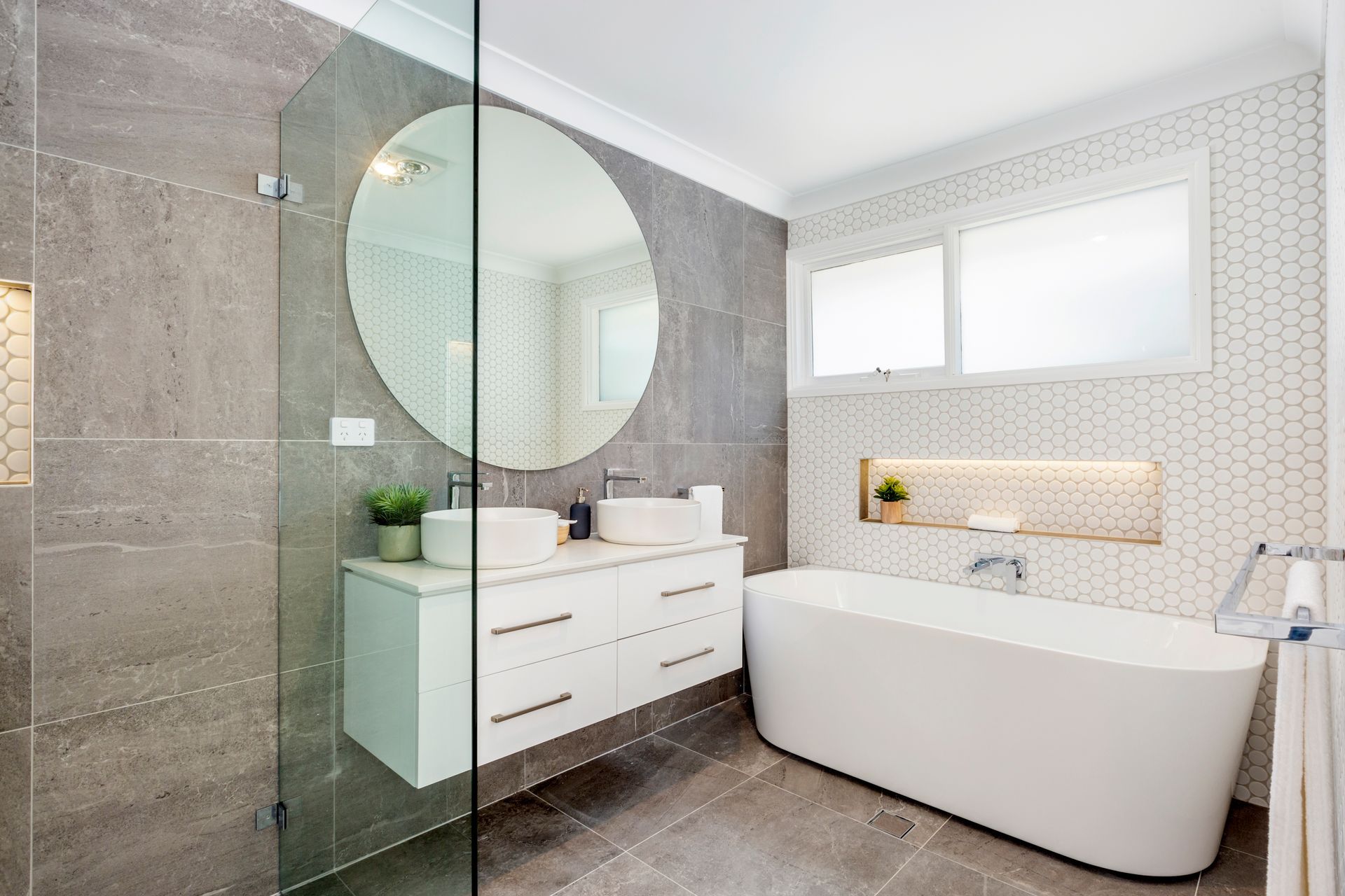 Blue-tiled bathroom with a glass shower, white vanity, and a window with frosted glass.