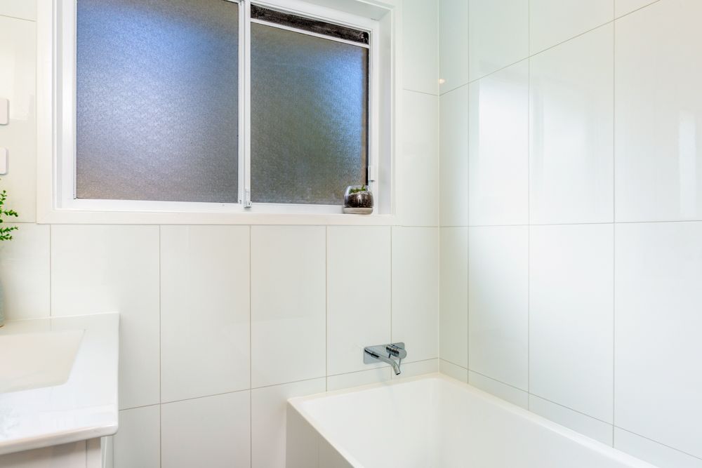 Backyard with lawn, patio furniture, and brick steps leading to a house under a blue sky.