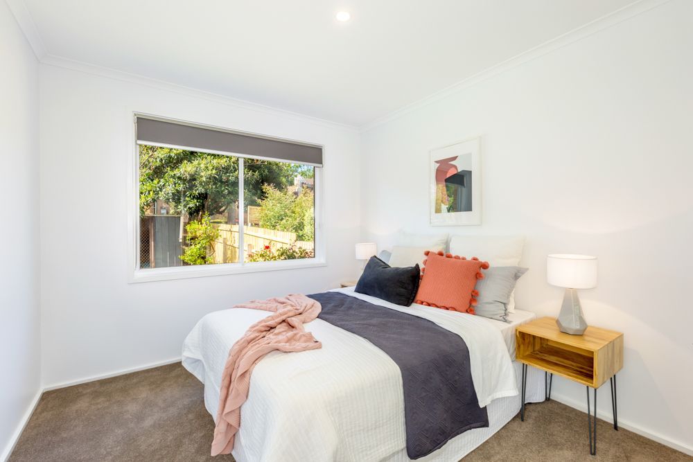 Living room with couch, armchair, wooden coffee table, rug, large window, and plants.