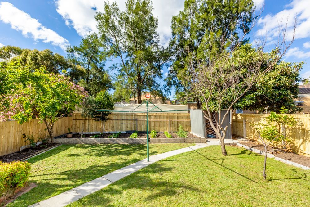 Brick home with small yard, green grass, and trees under a blue sky.