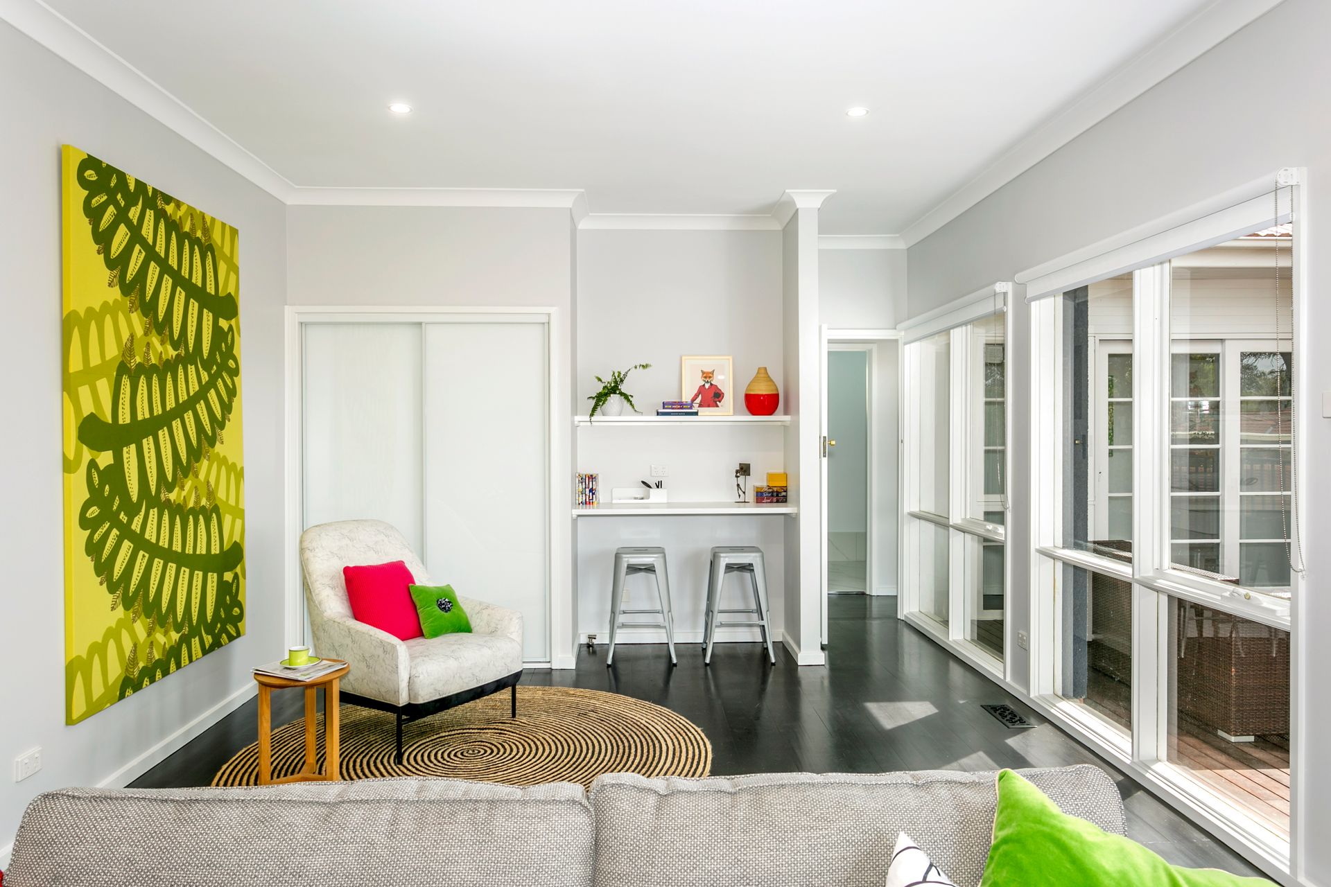 Living room with gray walls, white trim, and a colorful abstract painting. Features include a bar, armchair, and zebra rug.