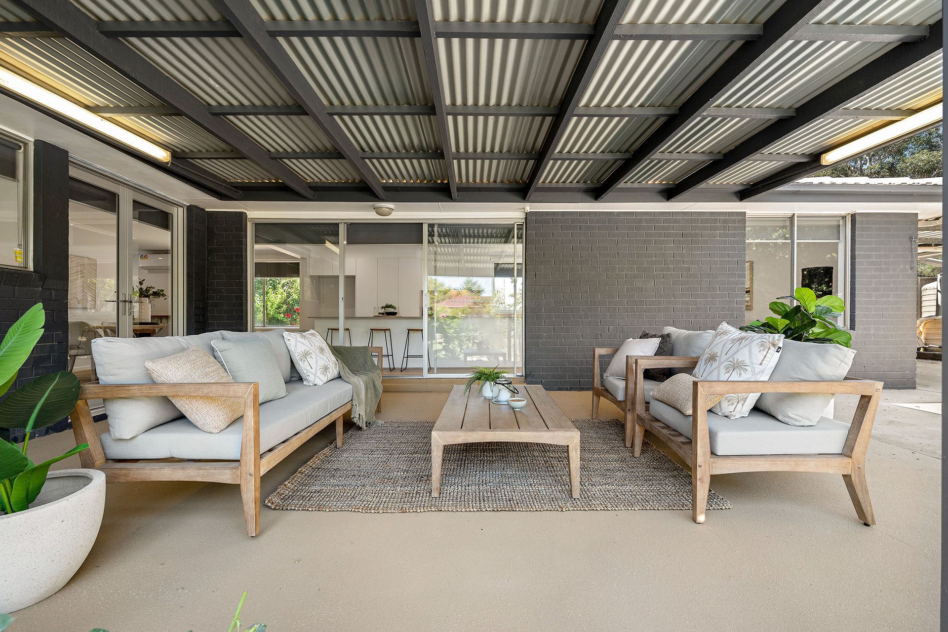 Covered patio with gray sofas, a wooden coffee table, and rug.