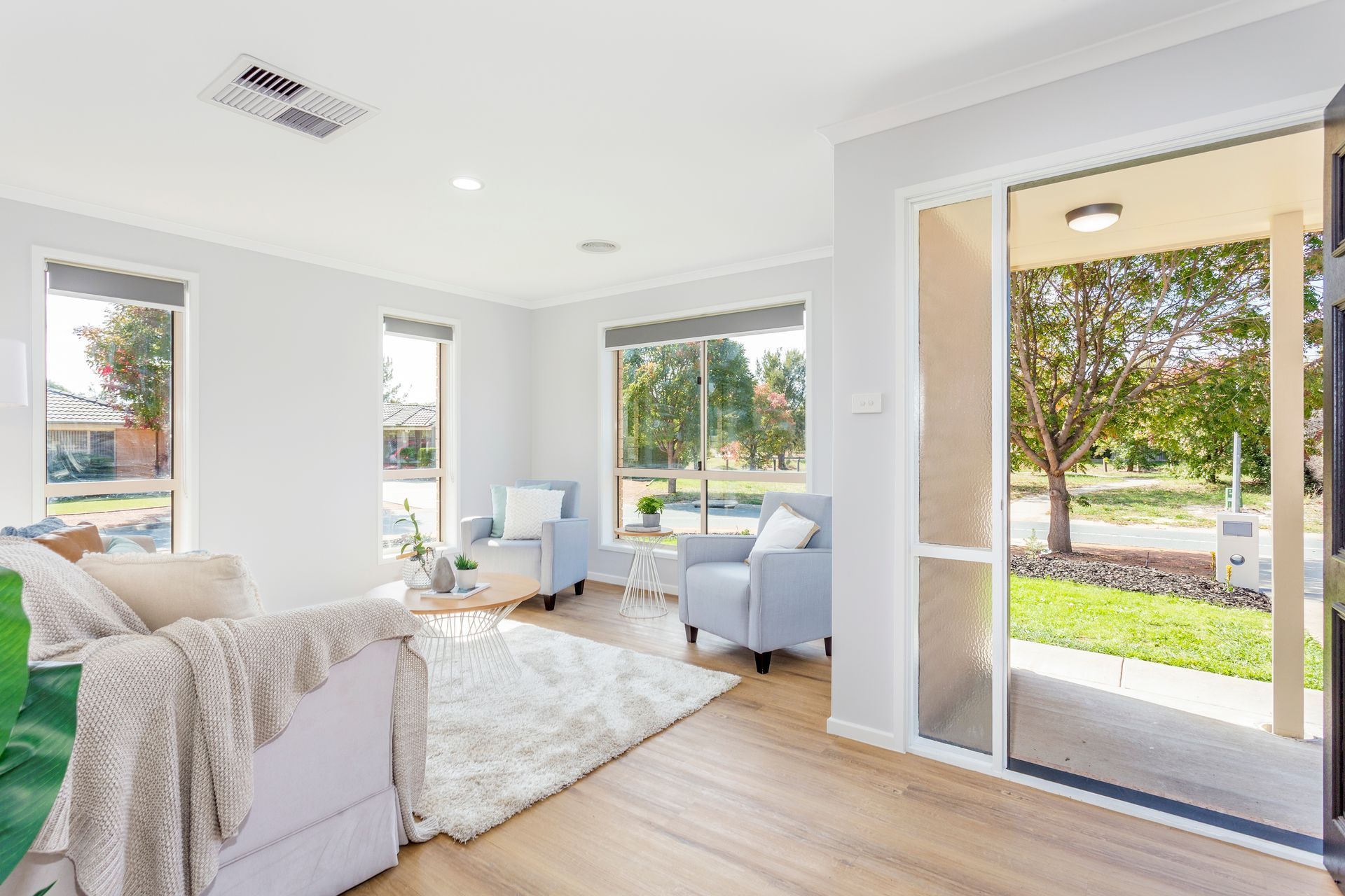 Living room with light gray walls, wooden floors, and a view of the outside through a large window.