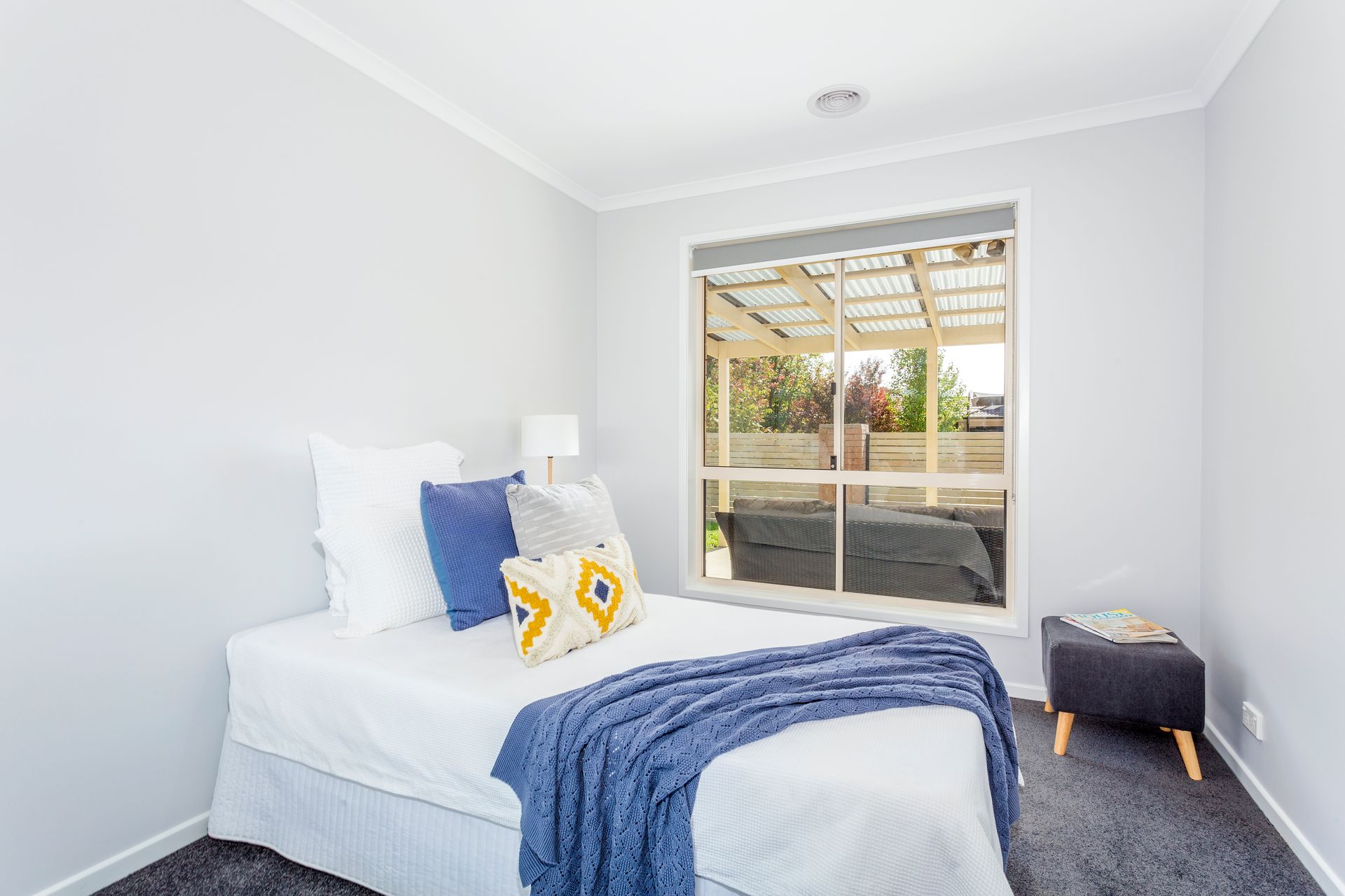 Bedroom with a bed, pillows, and a window overlooking an outdoor patio.