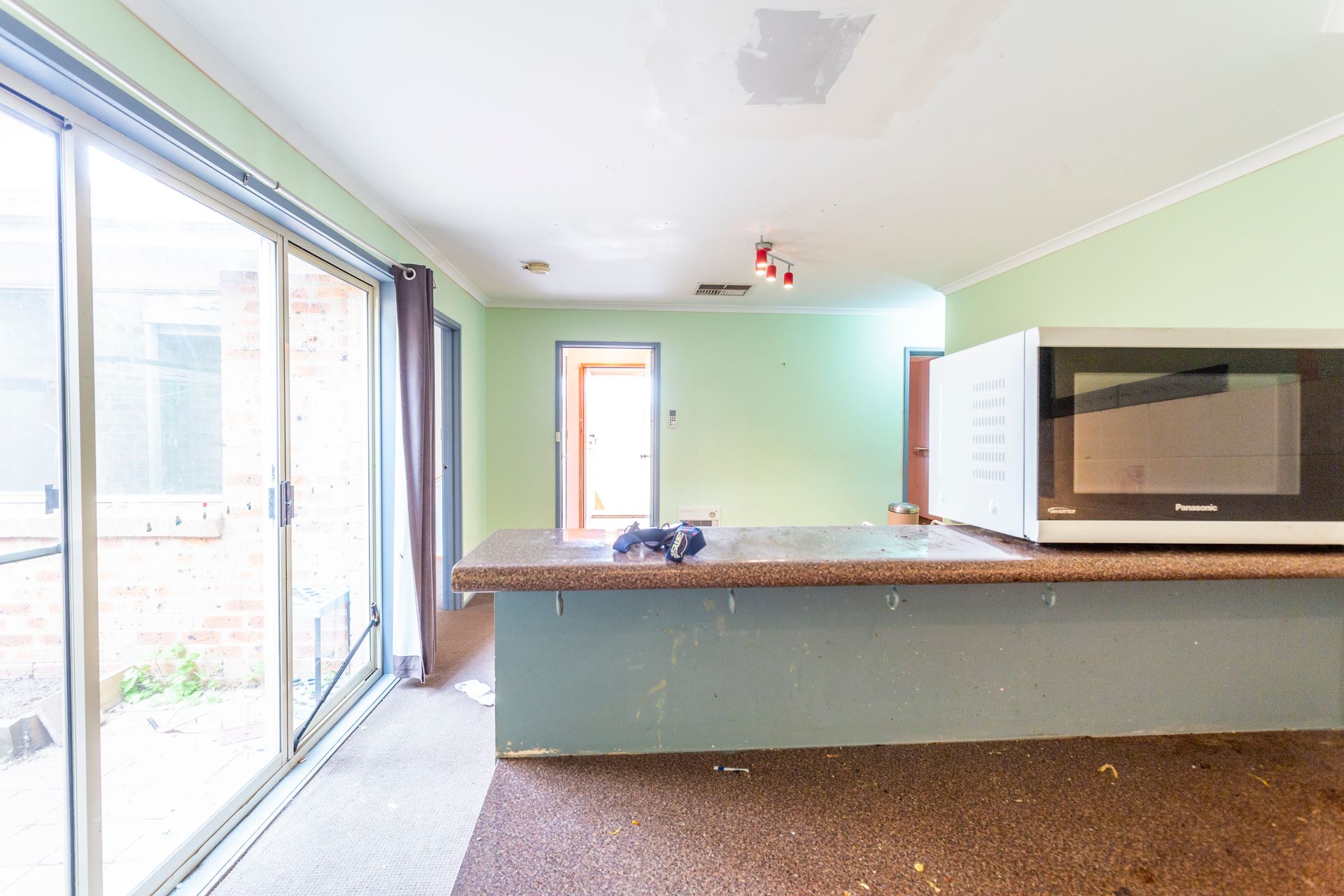 Kitchen with sliding glass door, countertop, microwave. Mint green walls, beige countertop.