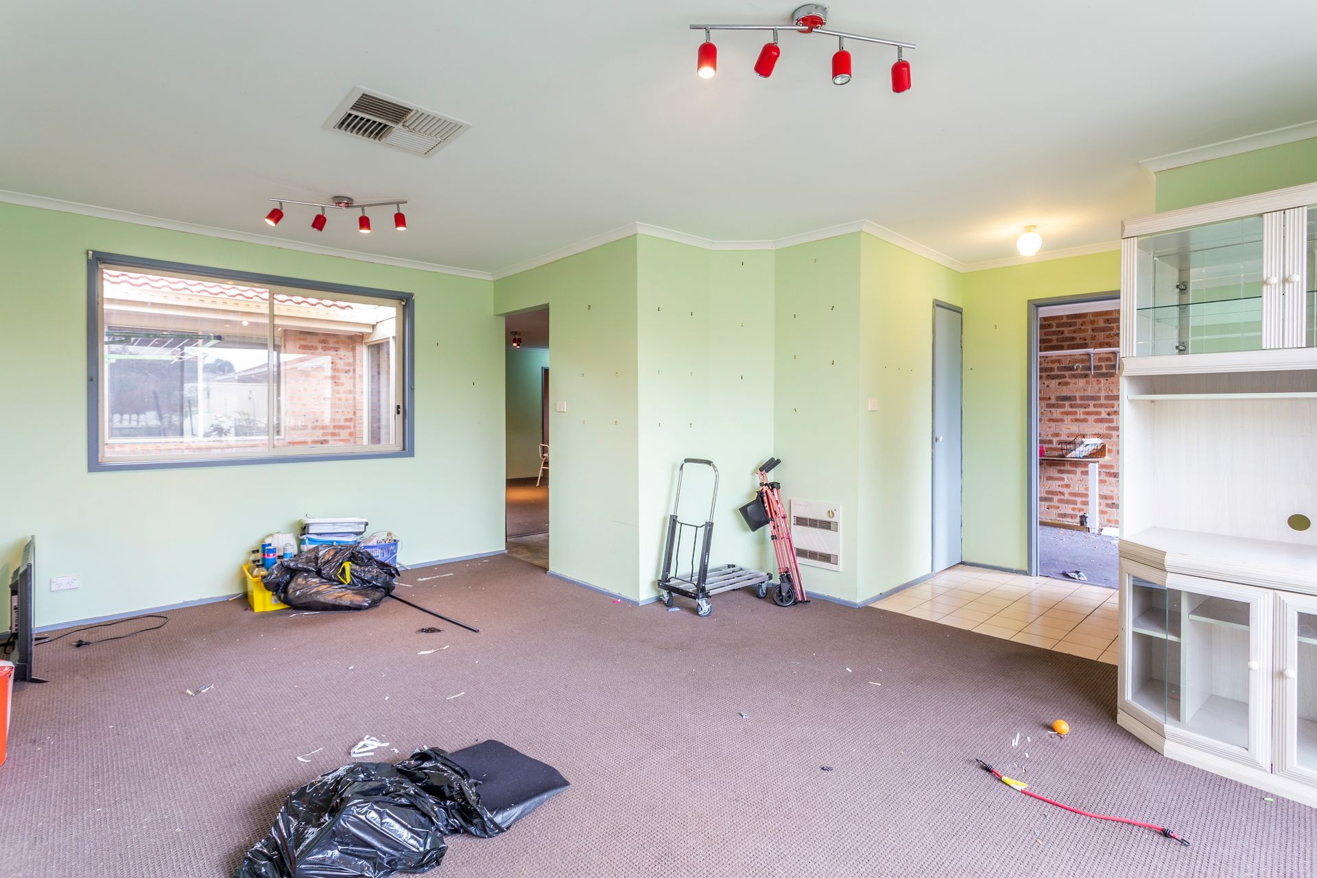 Interior of a messy living room with green walls and brown carpet, various debris scattered about.