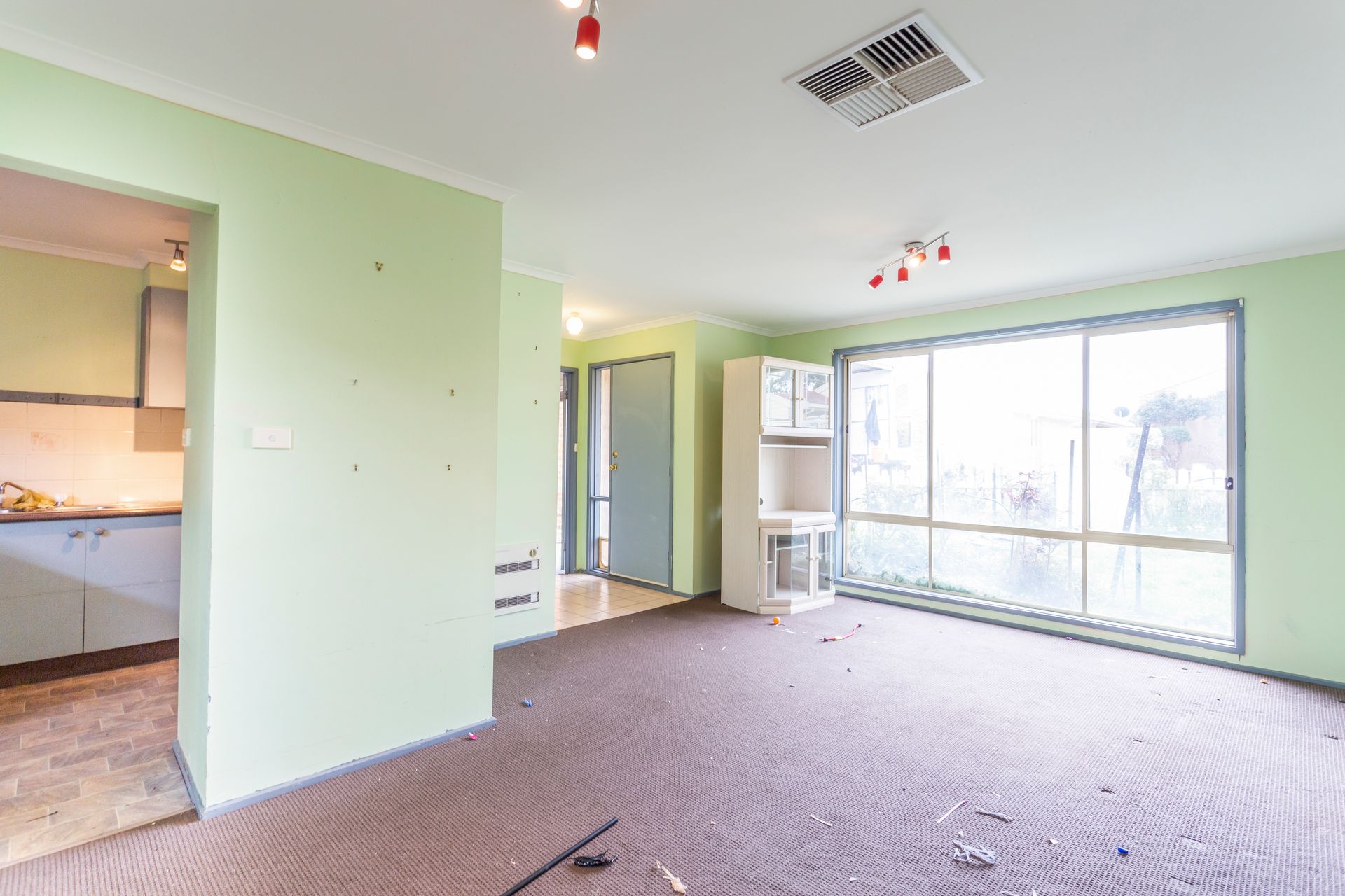 Empty room with green walls, a large window, and brown carpet.