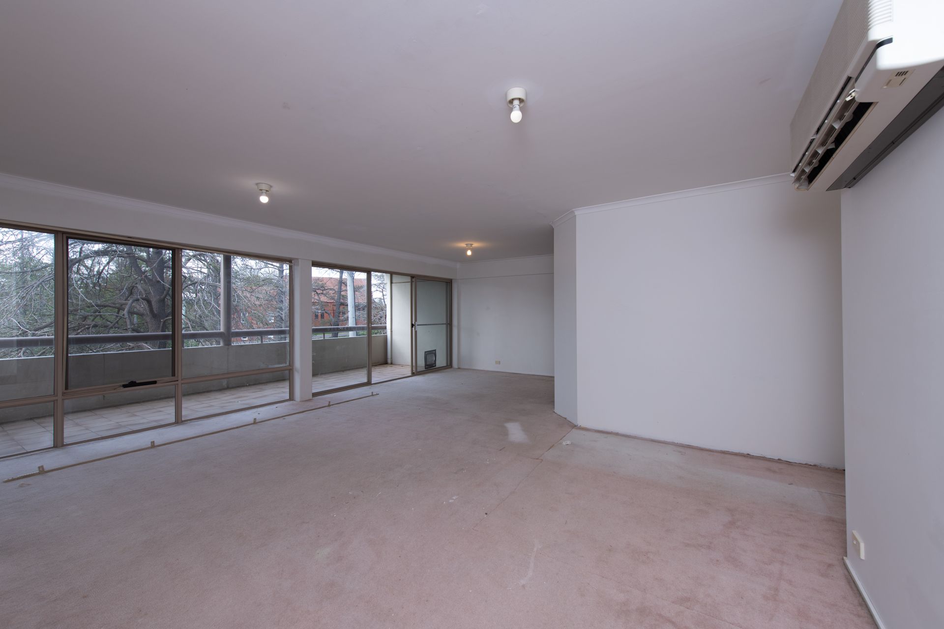 Small white kitchen with countertop and cabinets, in a neutral-toned apartment, light flooding the space.