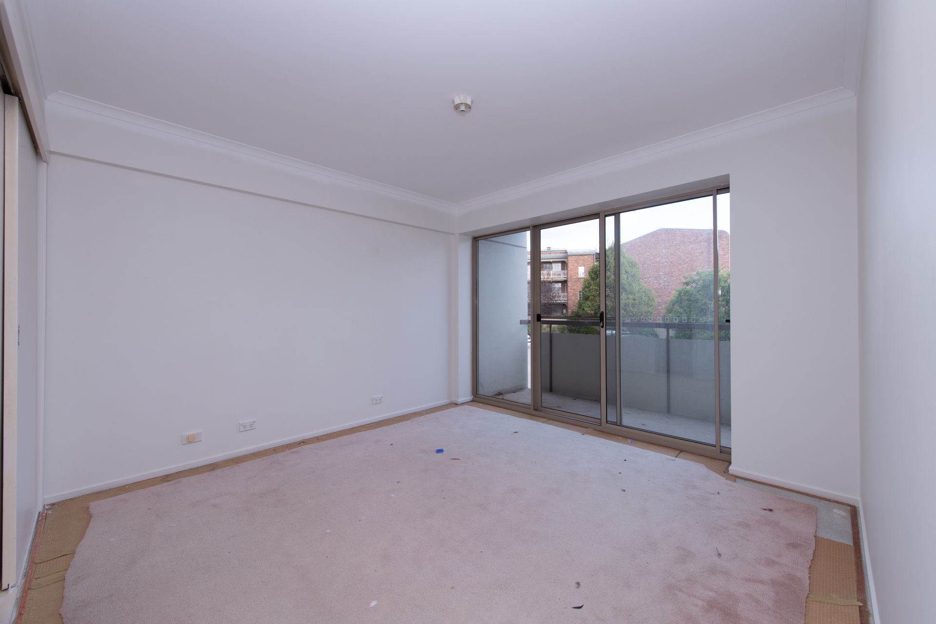 Empty room with stained carpet, sliding glass door, and white walls.
