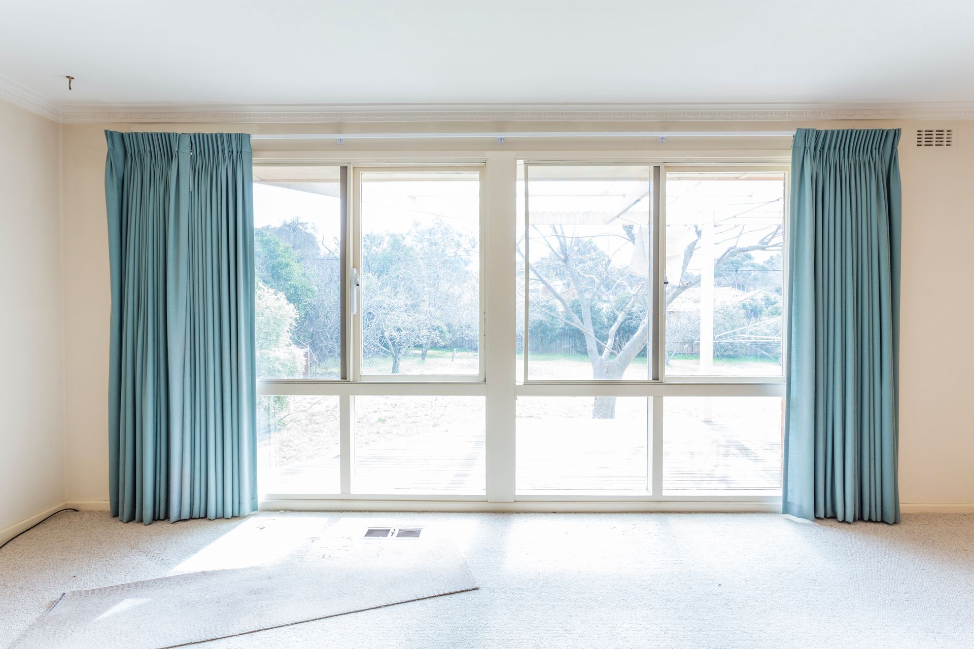 Large windows with light blue curtains. Room has a white ceiling, walls, and a light-colored carpet.