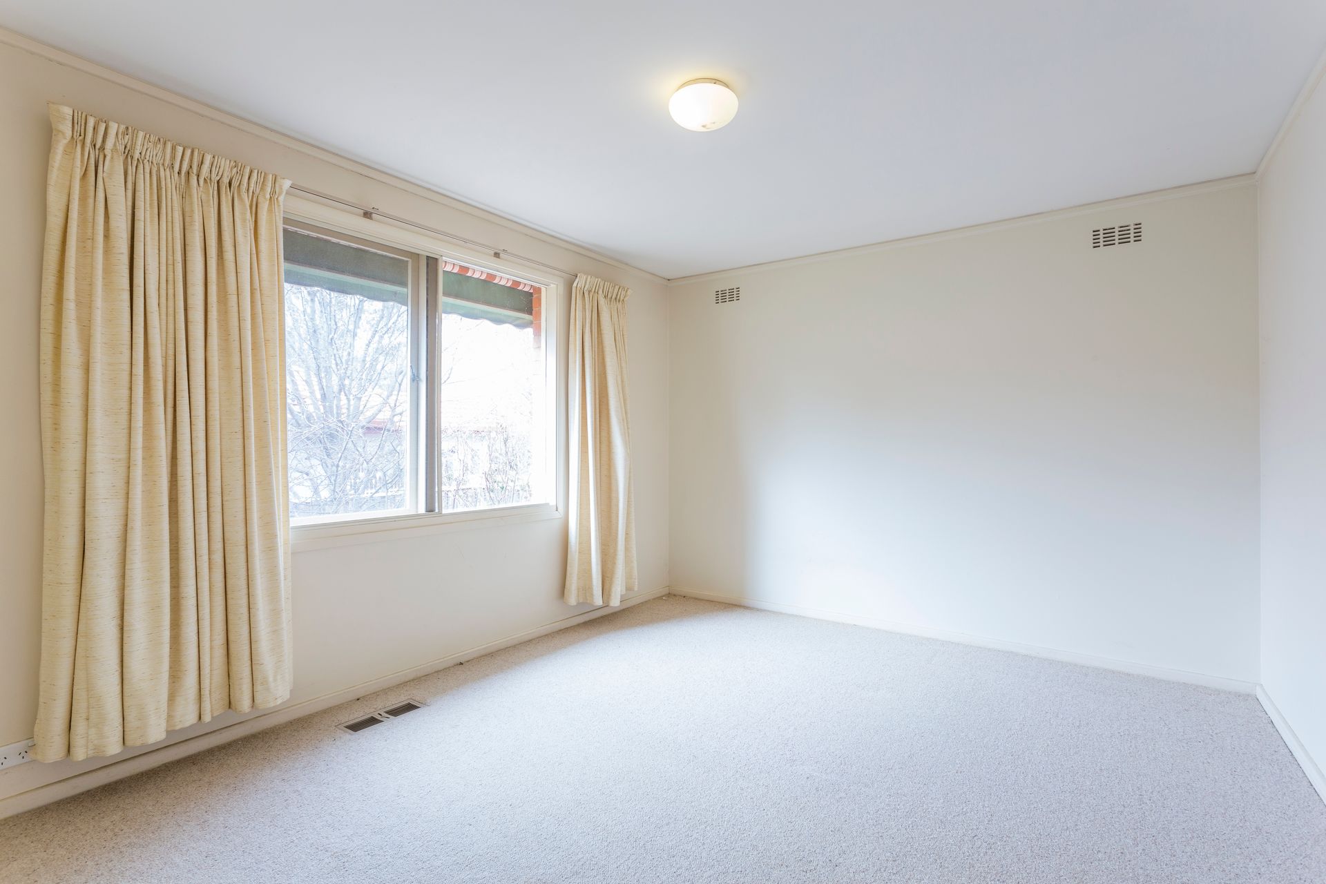 Hallway with beige walls, doors, and a light-colored carpet leading to an exterior glass door.