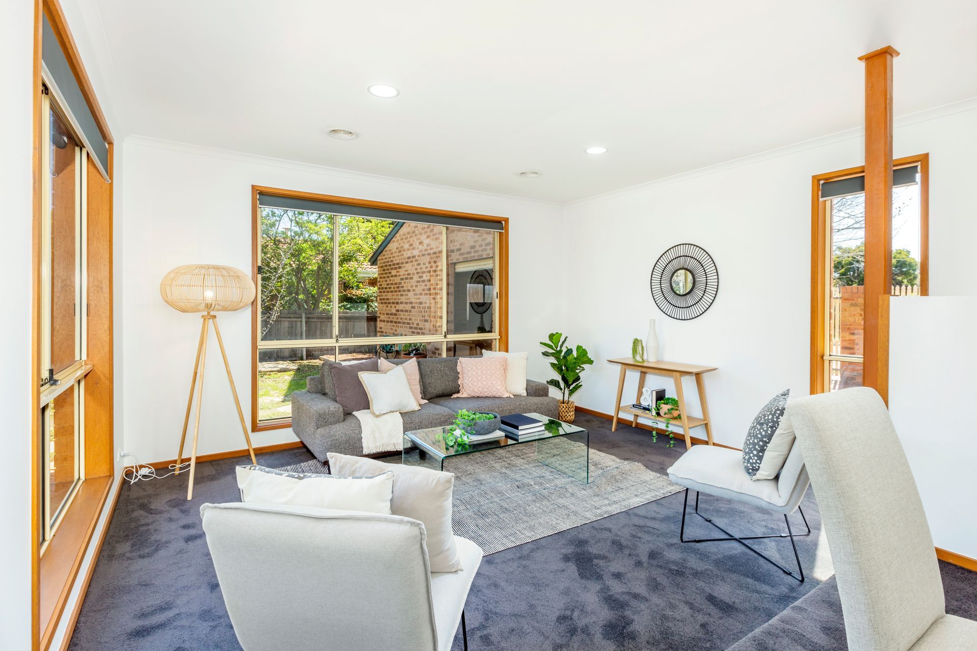 Living room with gray sofa, rug, and natural light from large windows.