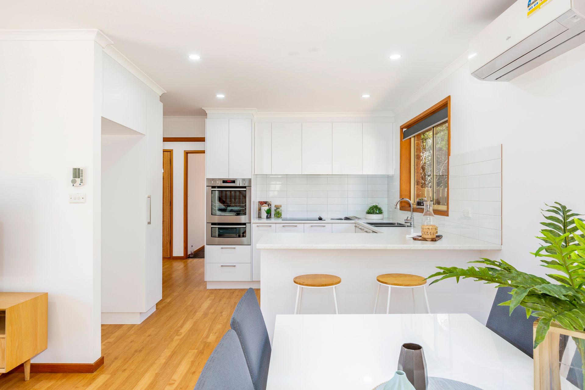 Modern white kitchen with a breakfast bar and dining table.
