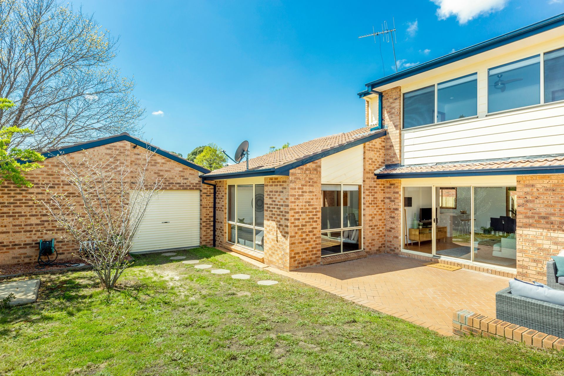 Brick house with a garage and backyard on a sunny day.
