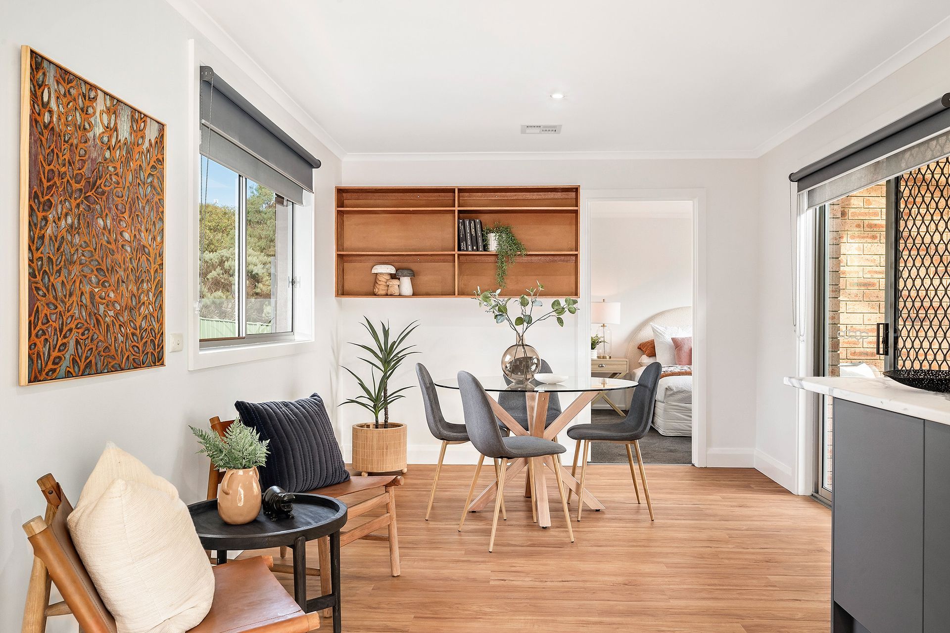 Dining room with table, chairs, art, shelves, plants, and natural light.
