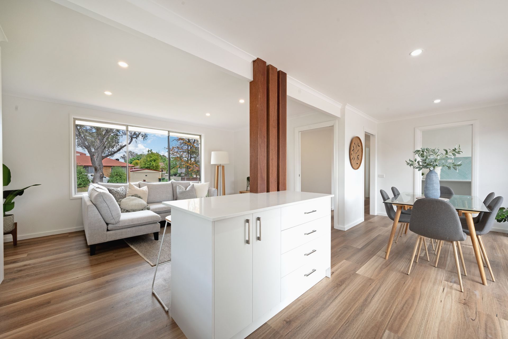 Dining room with table, chairs, art, shelves, plants, and natural light.