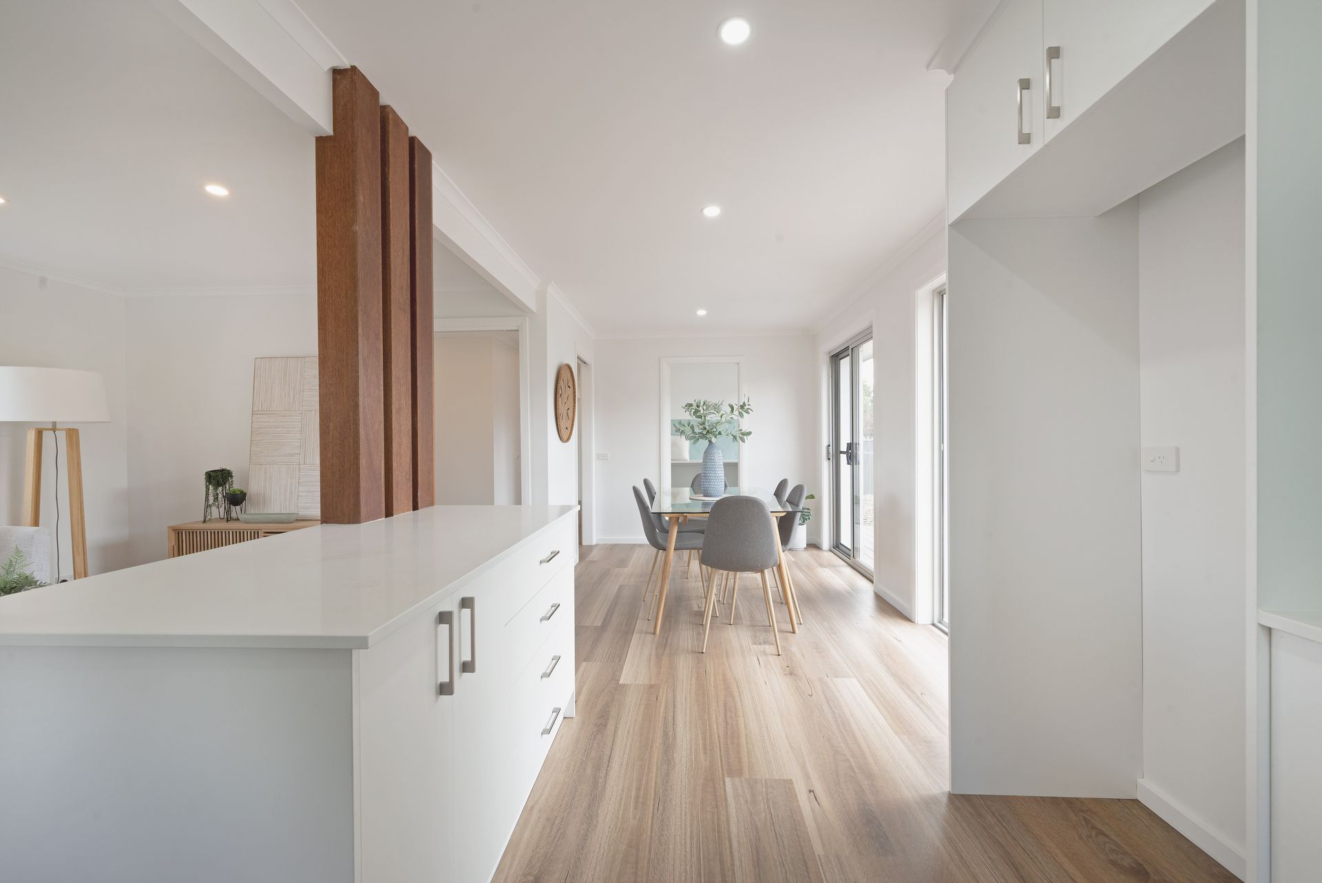 Bedroom with white walls, window, bed with orange and pink accents, two bedside tables, and a potted plant.
