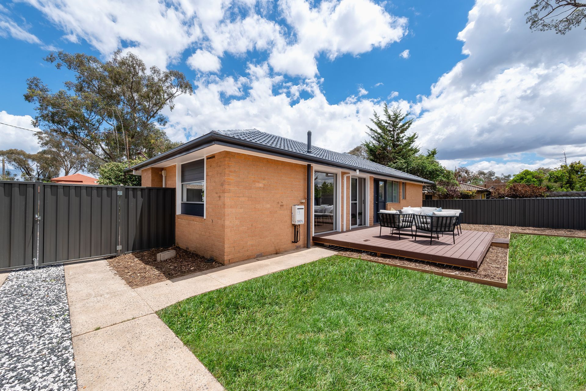 Living room with white walls, wooden floor, gray furniture, and large window.