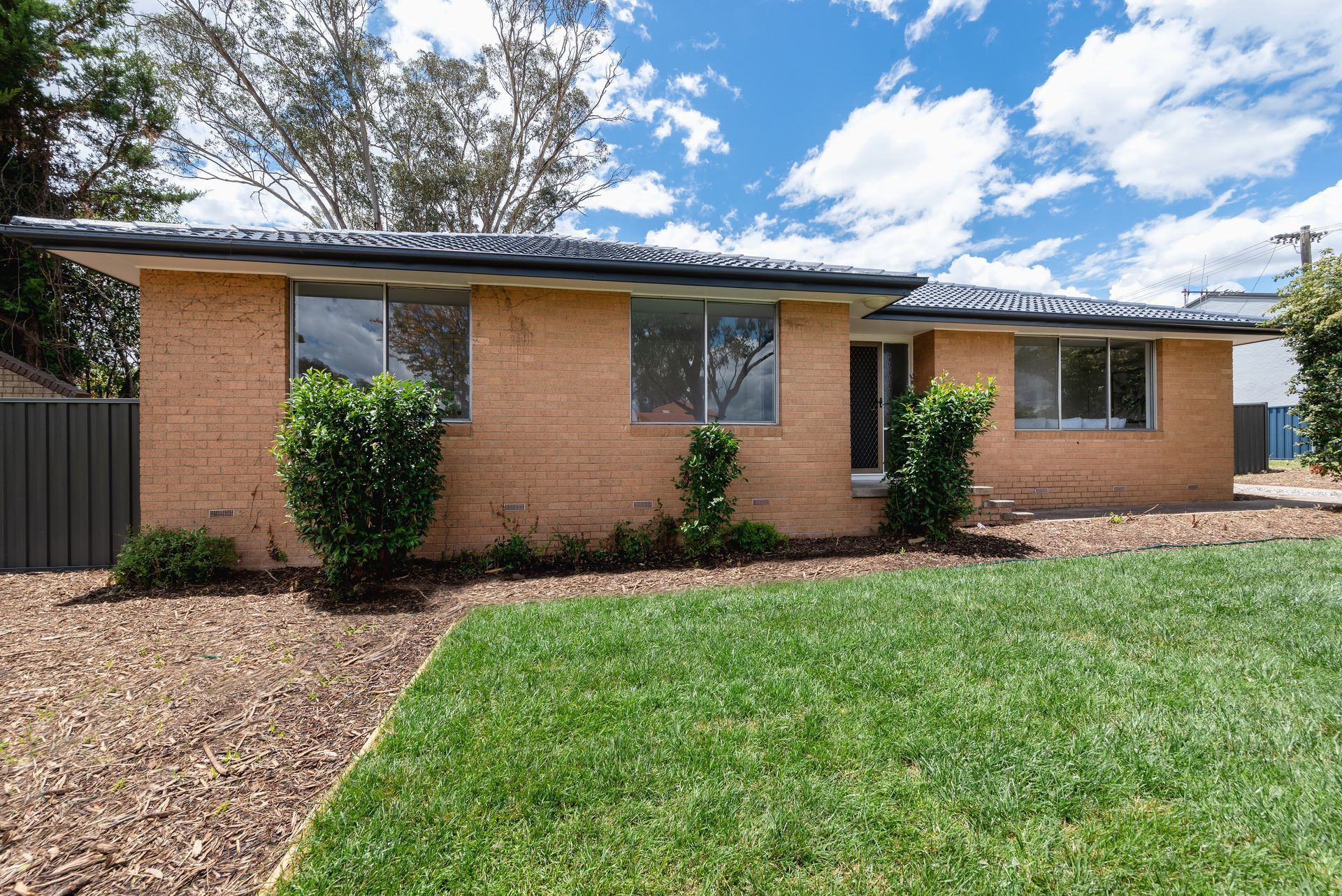 Brick house with a driveway and attached garage on a sunny day.