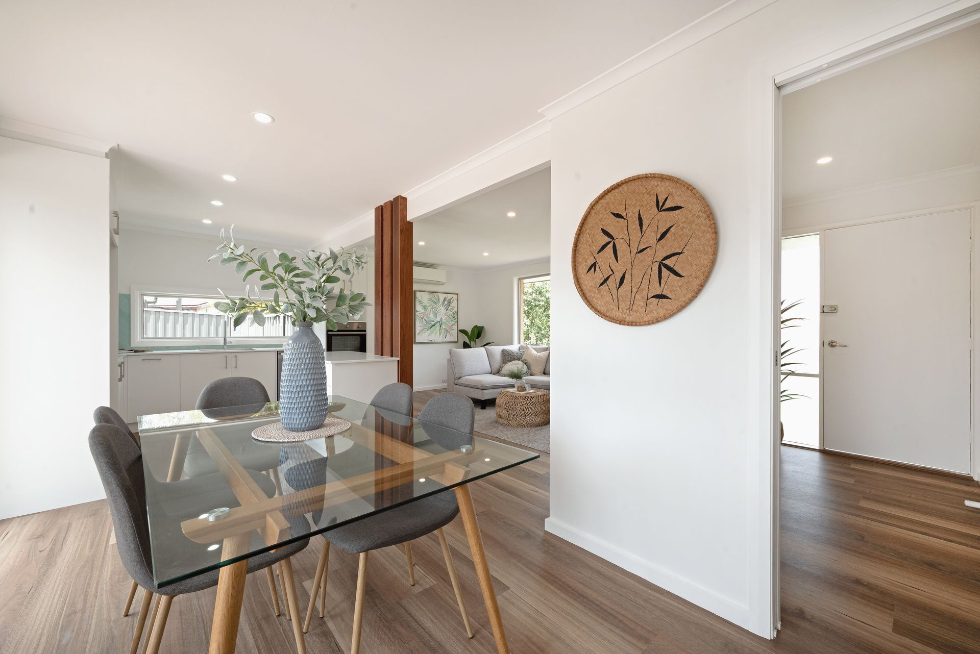 Bedroom with white walls, window, bed with orange and pink accents, two bedside tables, and a potted plant.
