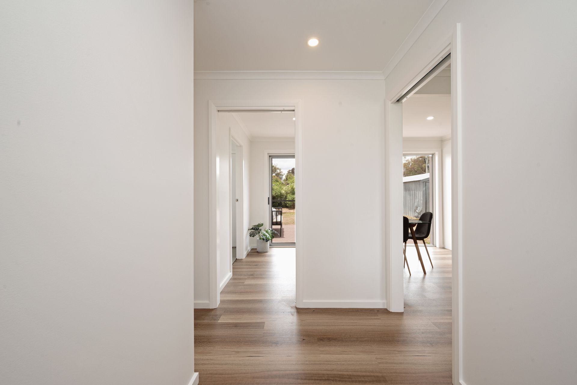 Dining room with table, chairs, art, shelves, plants, and natural light.