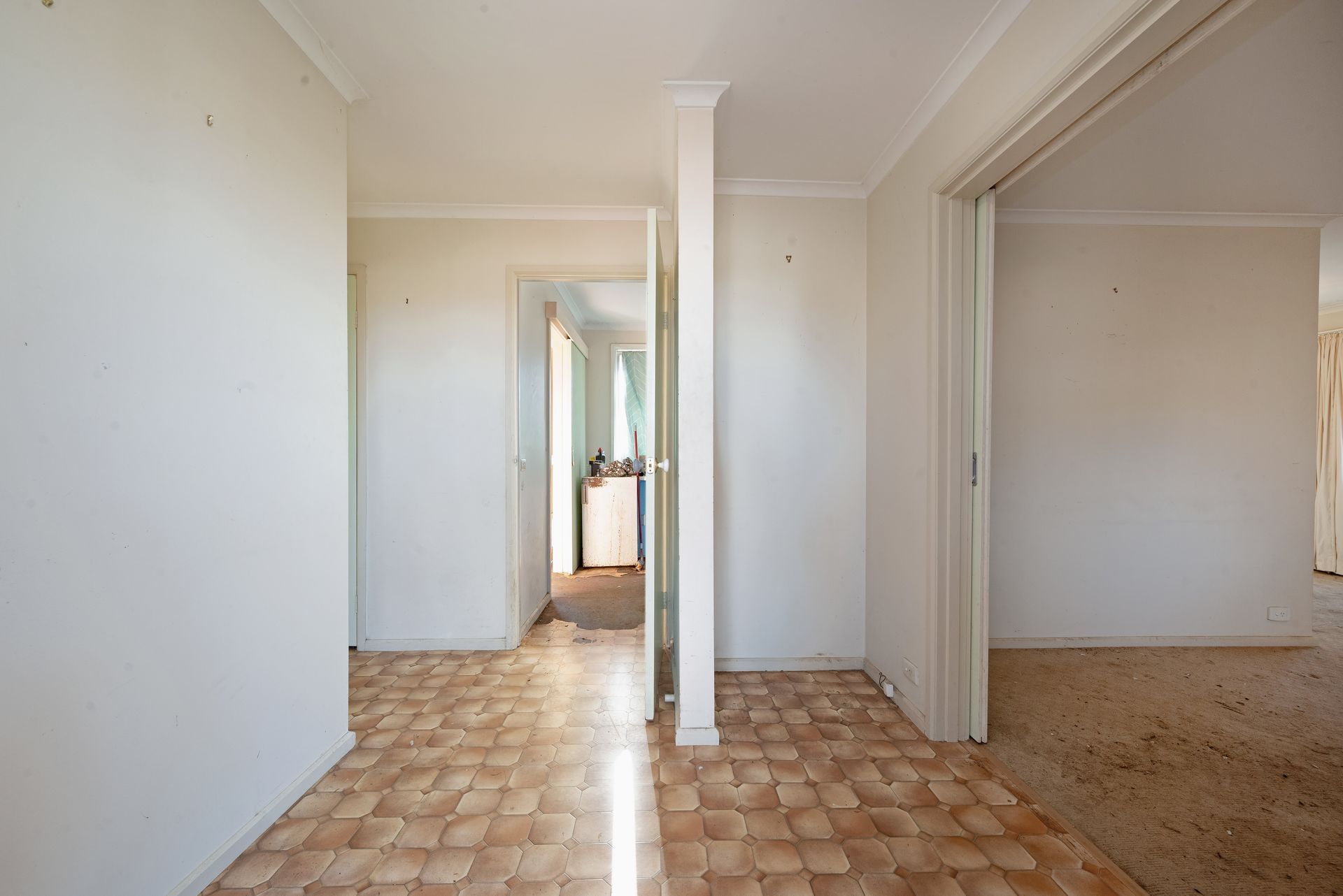 Living room with couch, shelves, boxes; natural light streams in.
