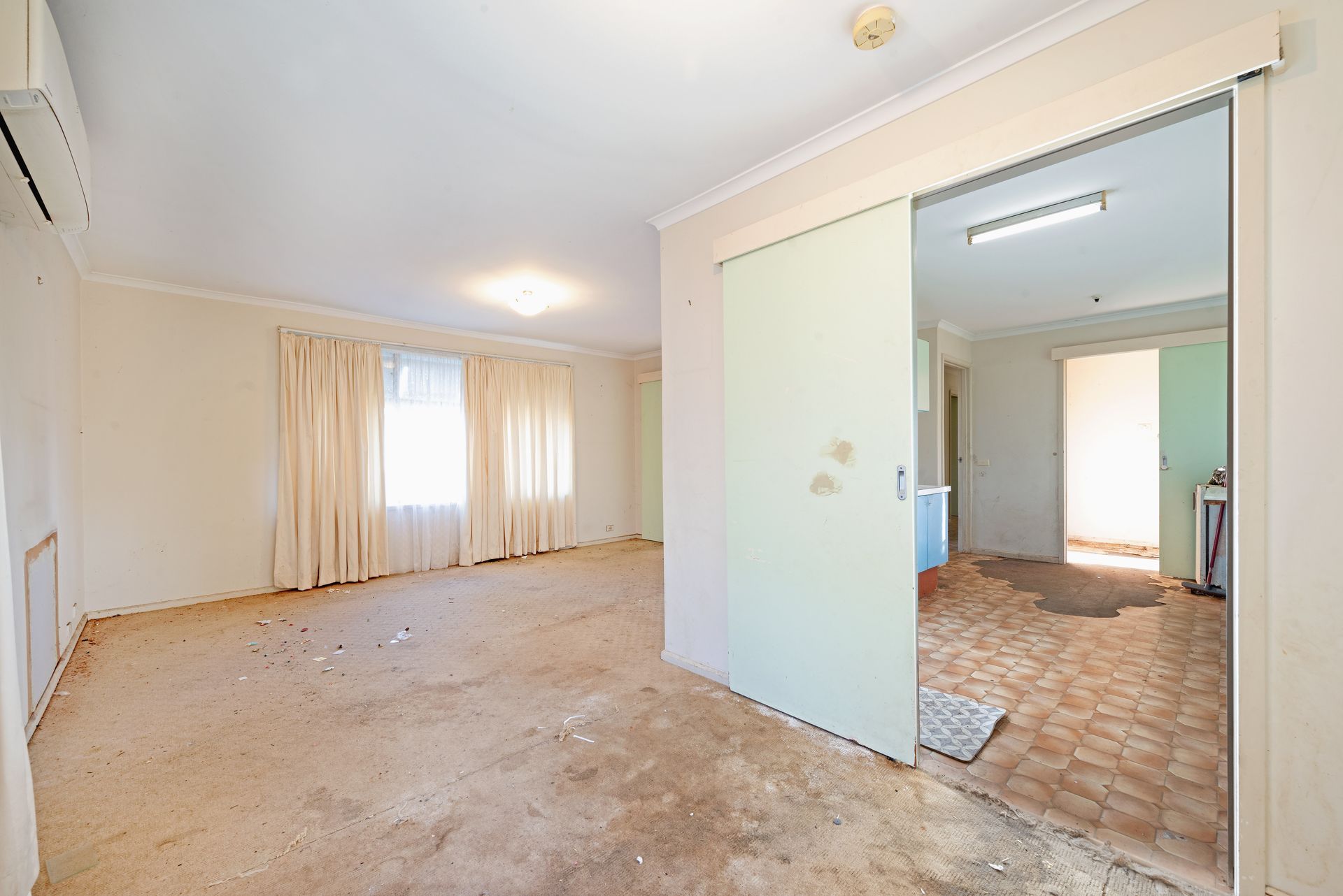 Living room with couch, shelves, boxes; natural light streams in.