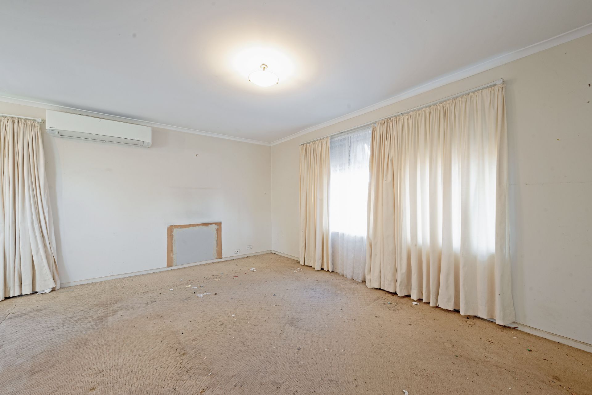 Living room with couch, shelves, boxes; natural light streams in.