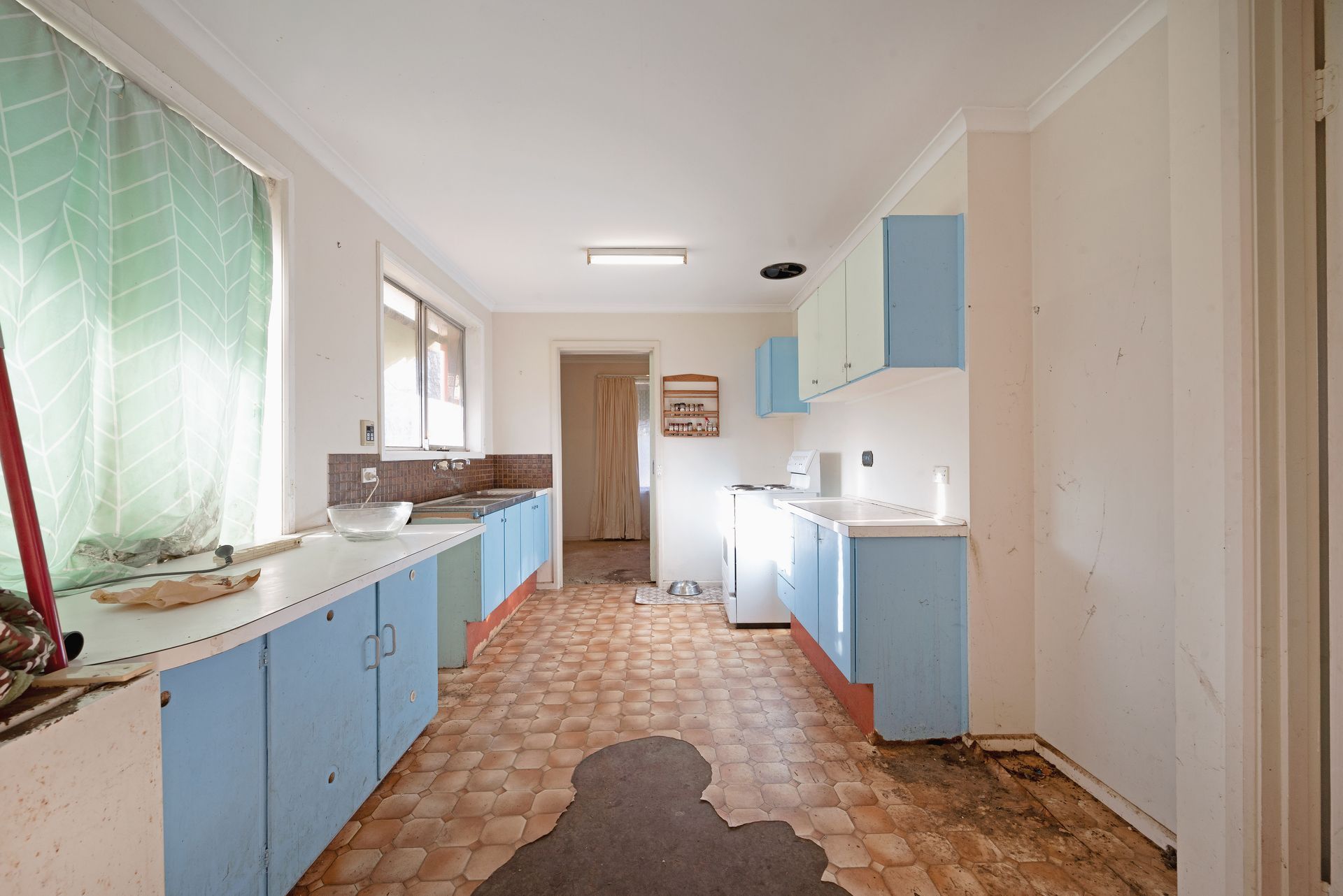 Laundry room with washing machine, sink, shelves holding cleaning supplies, and laundry baskets.