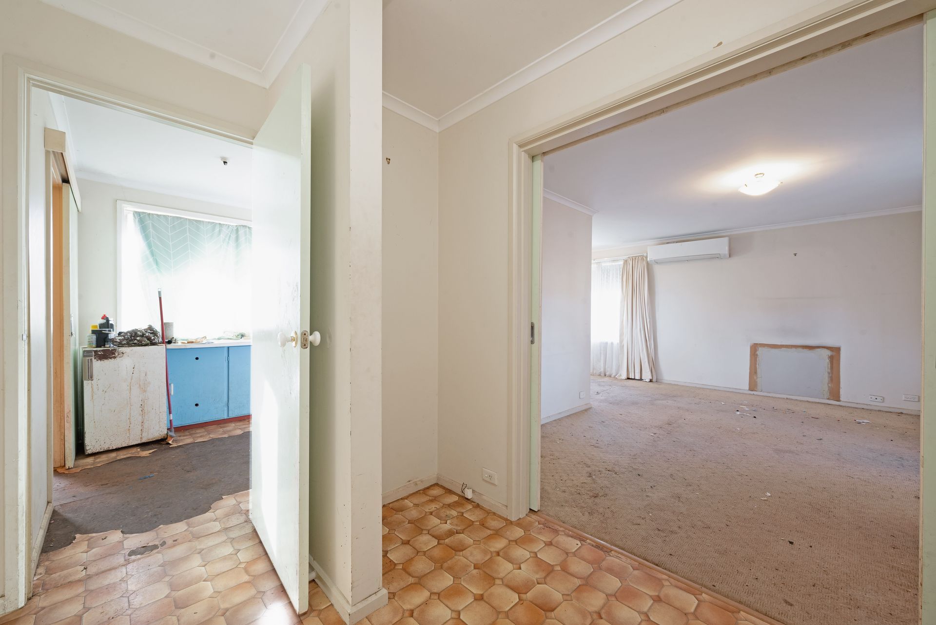 Empty bedroom with a bed, boxes, and a window. Beige walls and carpet.