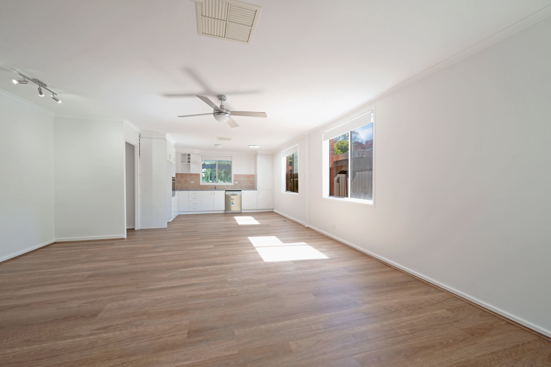 Open-plan interior with exposed brick wall, carpeted floor, and kitchen in the background.