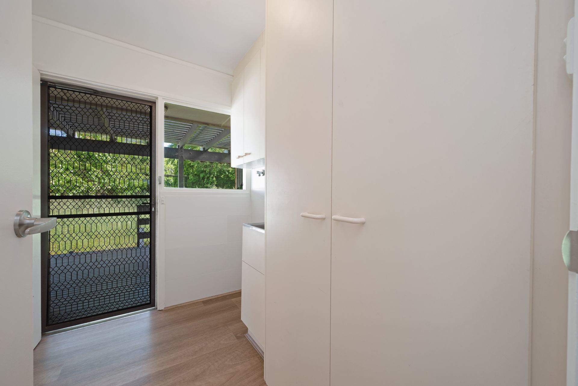 White interior room with tall storage cabinets and a screen door to the outside.