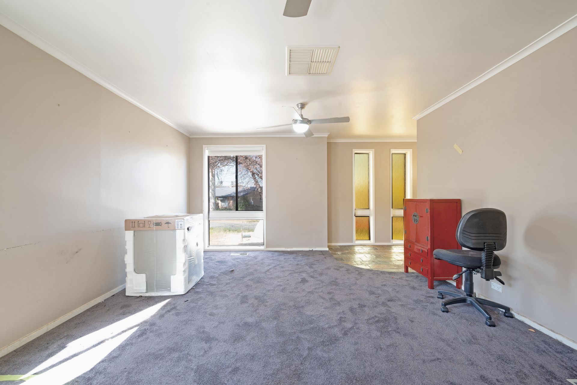 Open-plan interior with exposed brick wall, carpeted floor, and kitchen in the background.
