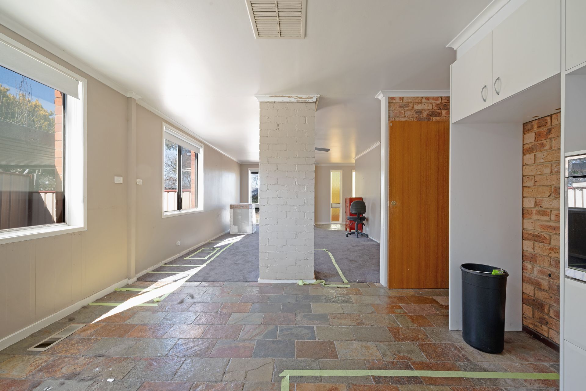 Empty interior room with exposed brick and tile flooring under construction.