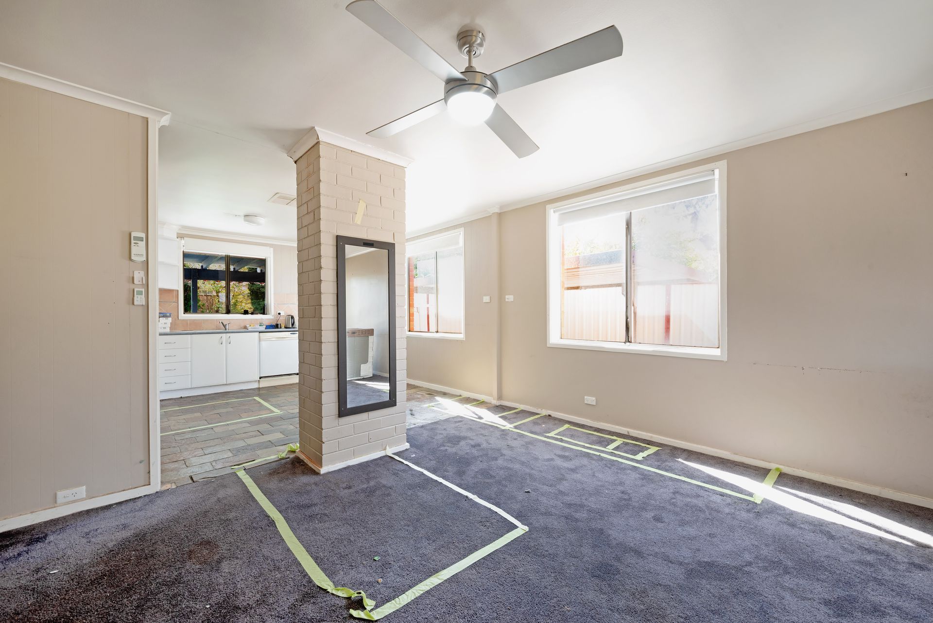 Bedroom with dusty blue carpet, pink curtains, a ceiling fan, and a hallway entrance.