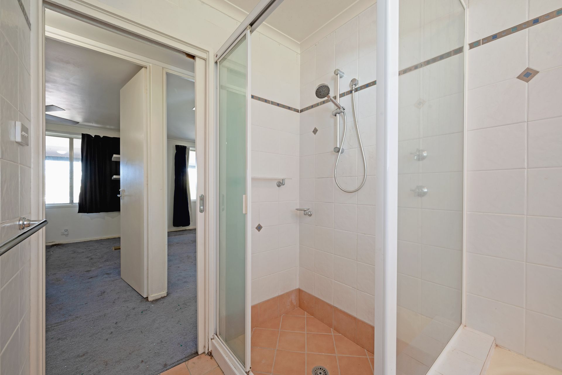 Open-plan interior with exposed brick wall, carpeted floor, and kitchen in the background.