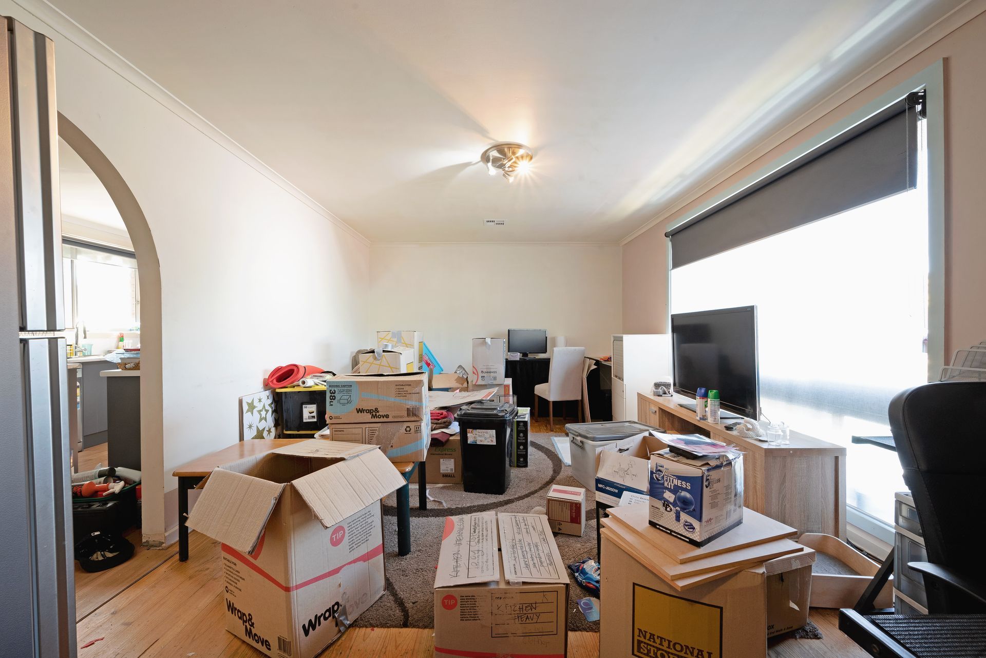 Living room filled with moving boxes and furniture, preparing for relocation.