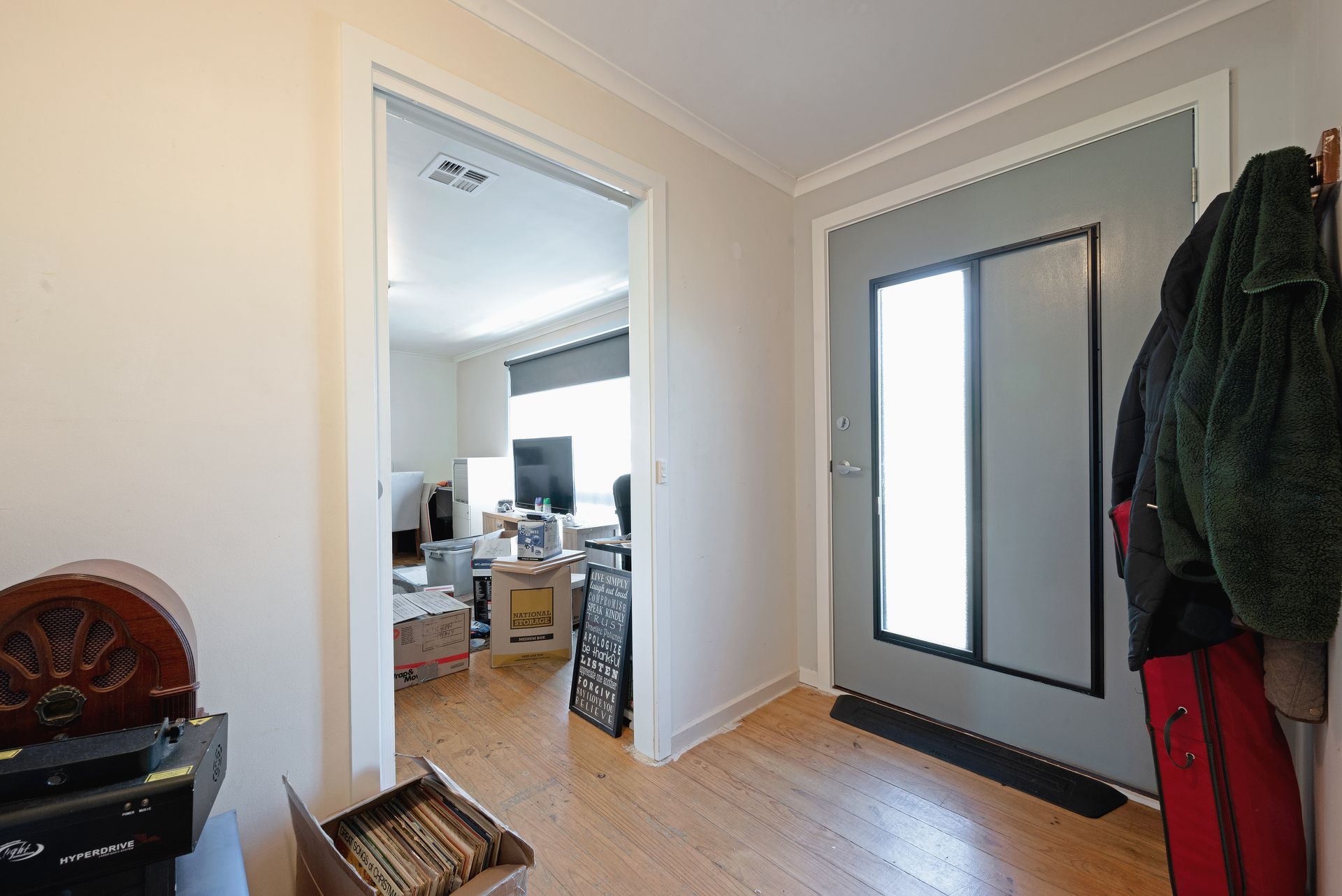 Hallway with door, interior door, record player, and coats hanging.