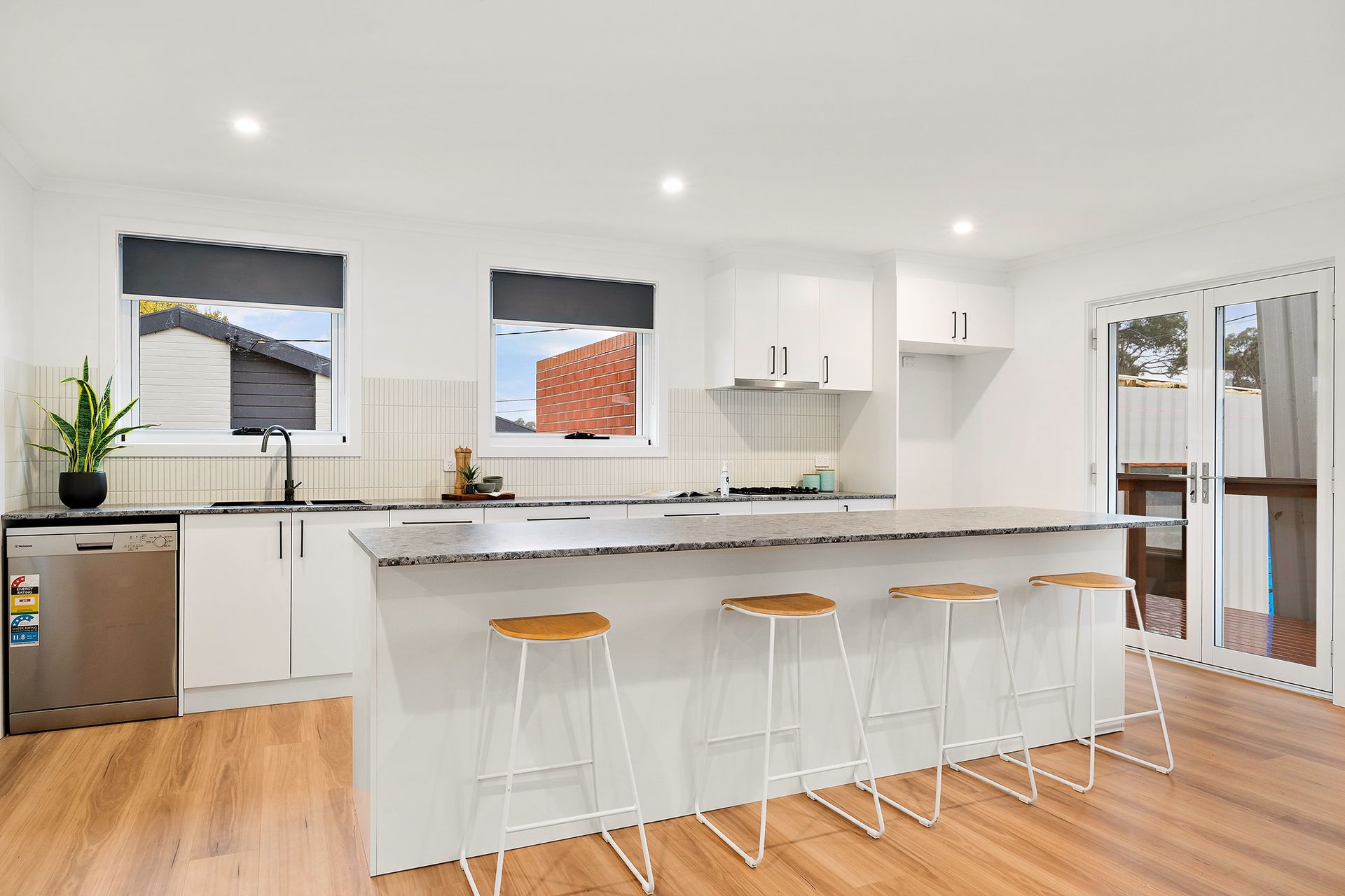 White laundry room with cabinets, counter, window, and shelves.