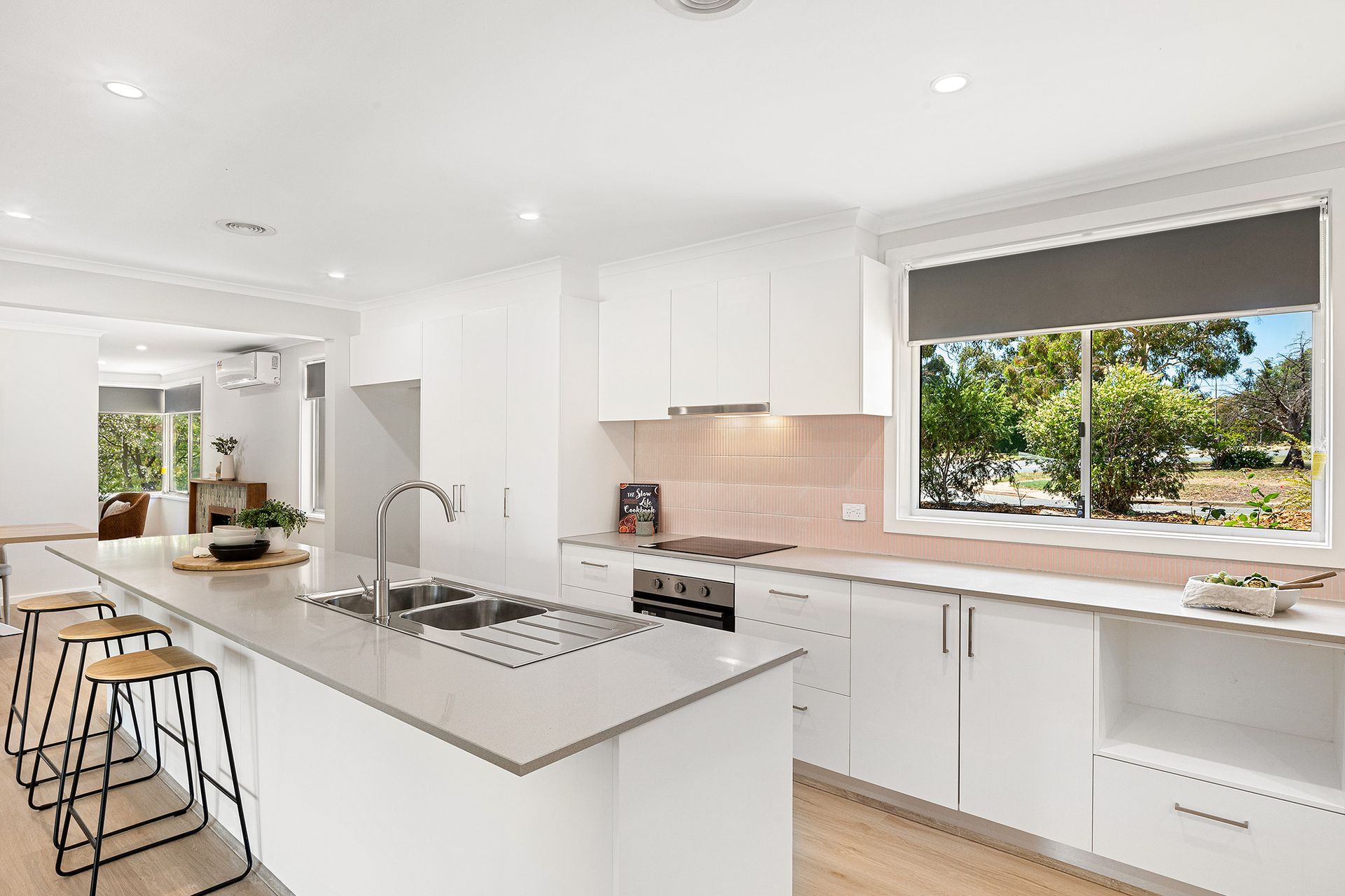 White laundry room with sink, counter, cabinets, and door to outside. Plant and laundry basket are present.