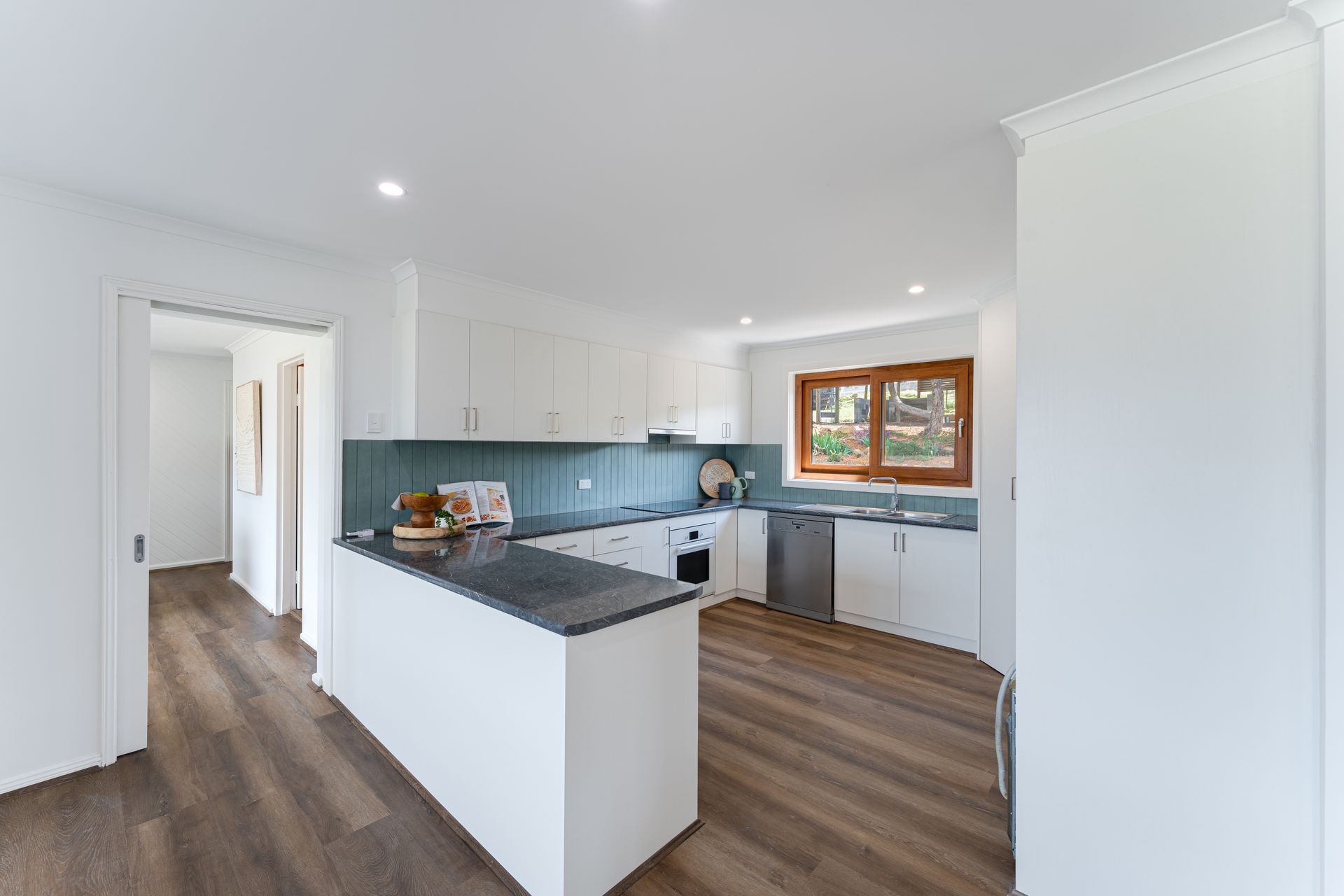 Bright, white kitchen with wood floors, blue backsplash, and a breakfast bar.