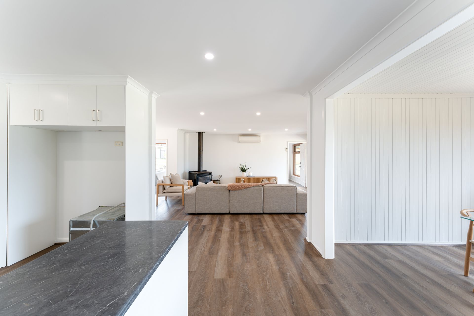 Spacious, open-plan living area with wood floors, neutral-toned furniture, and a fireplace.